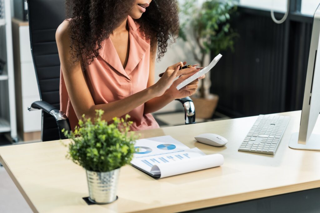 African American woman with afro at desk, managing finance, market research, investors for startup.