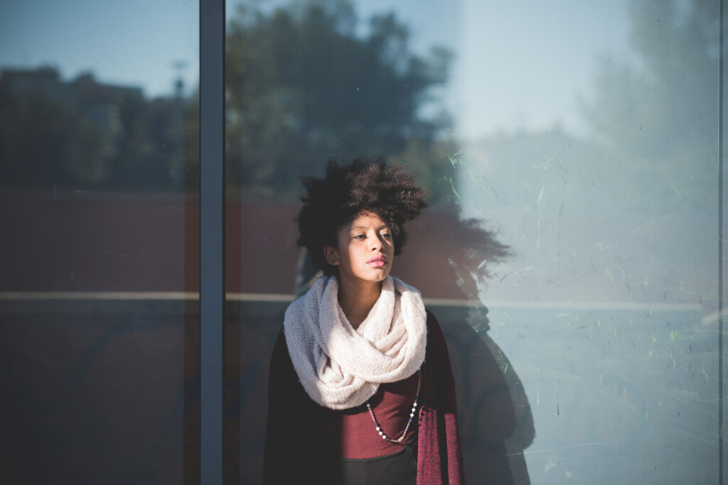 Young woman in natural light wearing a soft scarf and textured hair, reflecting understated style.